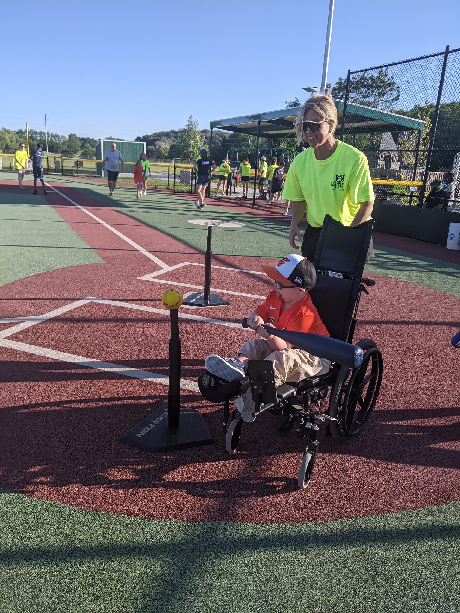 Miracle-League-of-Dane-County Batter in a wheelchair hitting a ball off of a tee.